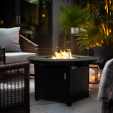 Burning aluminum 42-inch round fire pit table with nearby sofas, creating a cozy outdoor atmosphere in Oakville, Ontario.