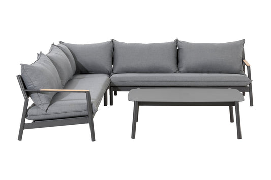 Full view of Monti sectional set, showcasing deep seating with teak wood armrests, frosted glass coffee table, and dark grey cushions.