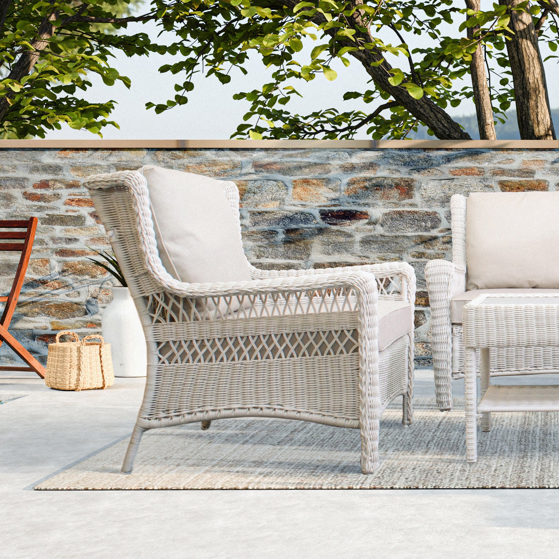 Park Meadows Wicker Outdoor Club Chair from the right side, with diamond weave details and wide armrests, set against a beautiful tree backdrop. Oakville, ON.