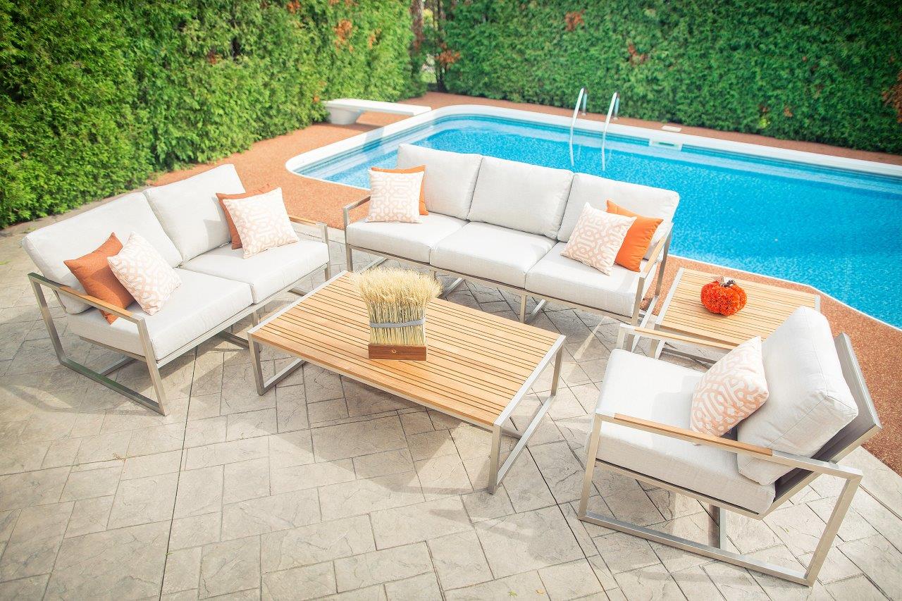 Front view of an Acacia coffee table with sofas on three sides, placed outdoors by a pool, showcasing a modern setup.